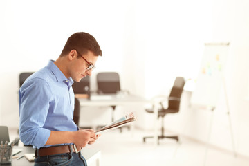 Handsome businessman reading newspaper in office