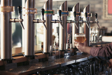 Bartender with glass of beer in bar
