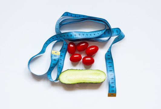 Blue measuring tape with tomato and cucumber on a white background
