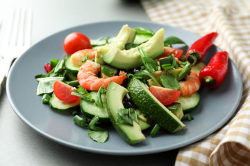 Plate with tasty avocado salad on table