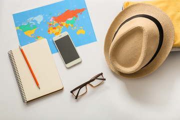Composition with world map, mobile phone, clothes and accessories on white background. Travel...