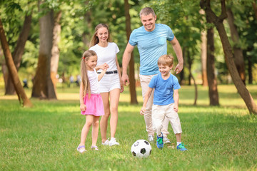 Fototapeta premium Happy family playing football in park on summer day