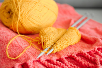 Knitting yarn with unfinished clothes on soft plaid, closeup