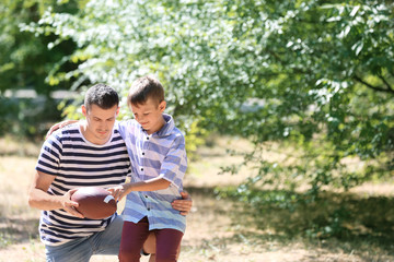 Dad and son with rugby ball outdoors