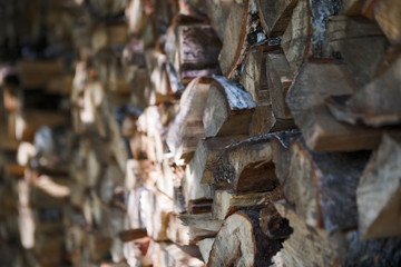 Stacked firewood harvested for winter. Rural landscape. Blur background