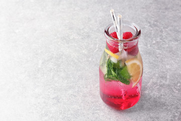 Bottle of fresh raspberry mojito on table