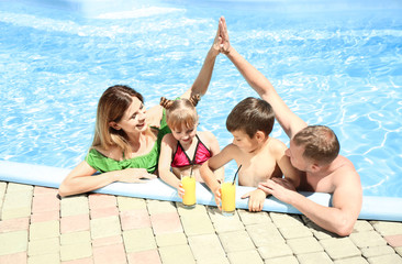 Happy family with glasses of juice resting in swimming pool