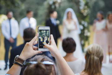 guest at the wedding ceremony takes pictures on the phone of the newlyweds