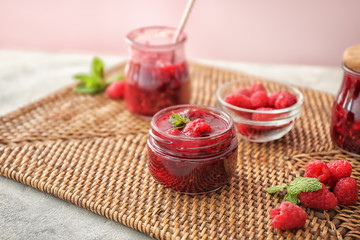Glass jar with sweet homemade raspberry jam on table