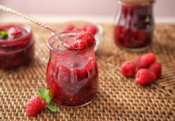 Glass jar with sweet homemade raspberry jam on table
