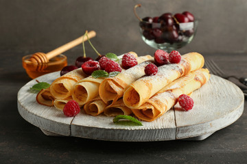 Stand with tasty pancakes and berries on dark table