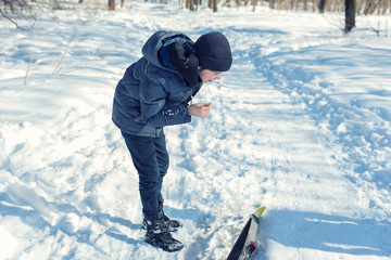 Fototapeta na wymiar Boy teenager on skis in a park of winter forest 