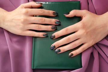 Hands of young woman with stylish manicure on notebook, closeup