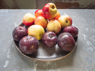ripe nectarines, red plums on a round ceramicceramic dish