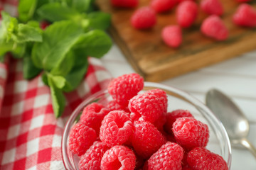 Bowl with delicious fresh ripe raspberries on table, closeup