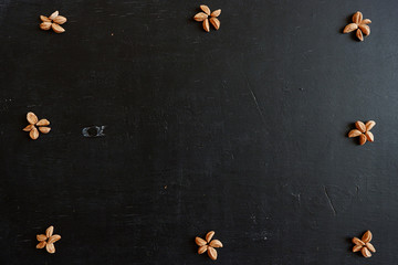 Black wooden background with a pattern. Seeds in the form of a flower on the board. Free space for design.