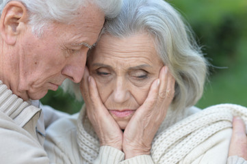 Close up portrait of sad senior couple in park