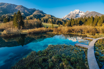 Fototapeta na wymiar Sunrise view of Zelenci National Park and Nature reservation in Slovenia, Julian Alps. Sunset or sunrise over an alpine lake with blue water and sky. Alpine mountain landscape, river and lake.