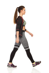 Walking Young Woman In Sports Clothes And Striped Leggings. Side View.