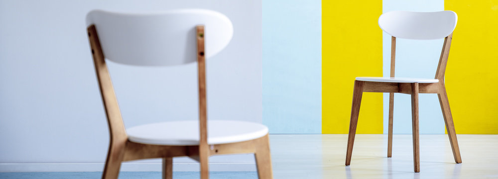 Panorama of white wooden chairs in living room interior with blue and yellow wall. Real photo