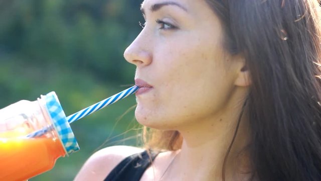 Woman drinks smoothies or orange fresh outdoors.