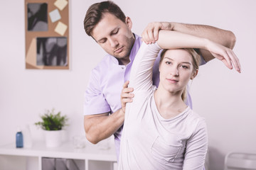 Professional physiotherapist and patient exercising with arm during physiotherapy
