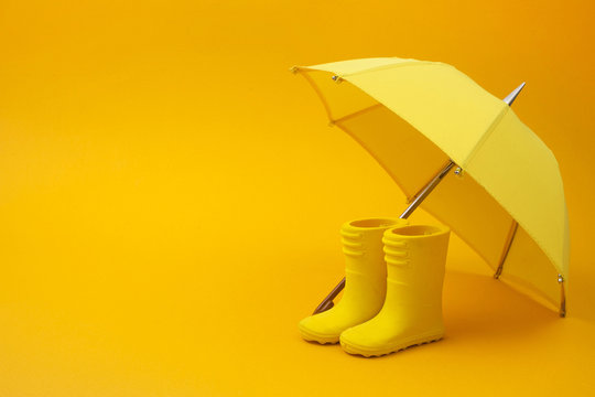 A Pair Of Yellow Rain Boots And A Umbrella On A Yellow