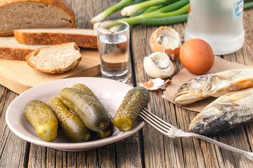 Vodka with traditional Slavonic snacks on table - hering,  pickled cucumber, egg and onion