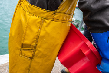 Detail of a commercial fisherman's traditional waterproof yellow oilskins.