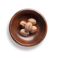  nutmeg in a wooden bowl, isolated on white