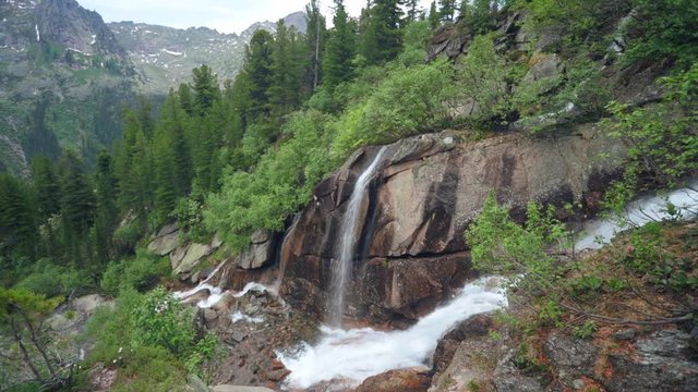 Великолепный горный пейзаж с водопадом. Красивый горный ручей и волшебные горные цветы 