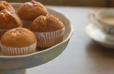 Fresh muffins on wooden table and cup of tea, side view