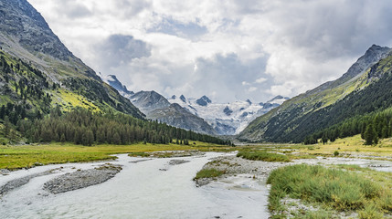 Naklejka na ściany i meble Mountain landscape in the Roseg valley below the melting glaciers and summits of the Sella Group and Piz Roseg