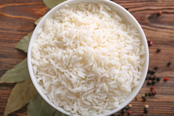 Bowl with boiled white rice on wooden table