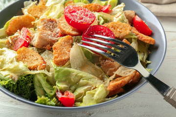 Plate with tasty Caesar salad on table, closeup