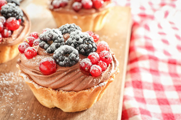 Tasty tartlets with berries on wooden board