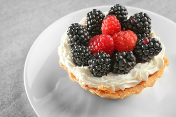 Tasty tartlet with whipped cream and berries on plate, closeup