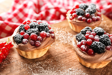 Tasty tartlets with berries on wooden board