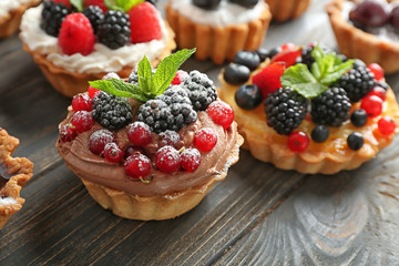 Tasty tartlets with berries on wooden table, closeup