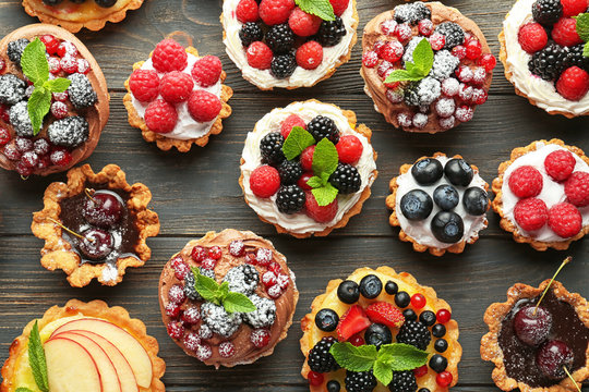 Tasty tartlets with berries on wooden background, top view