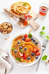 pancakes with blueberry strawberry honey and nuts for breakfast