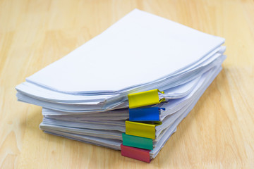 Color paper clip with Stack of papers documents on wood table in office 