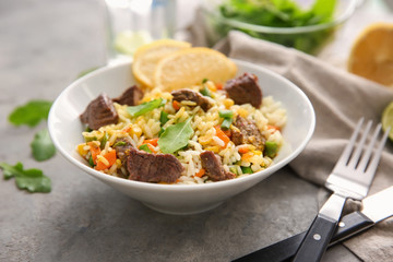 Delicious boiled rice with meat and vegetables in bowl on table