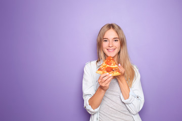 Young woman eating slice of delicious pizza on color background