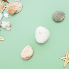 Flat lay. Top view. Frame of shells of various kinds on a green blue background. Seashells and starfish on a pastel background. Vacation concept