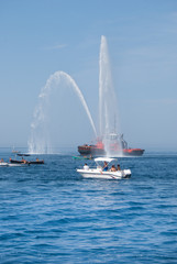 Ship of the fire brigade with high splashes and some boats under high