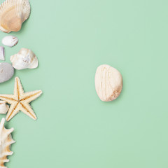 Flat lay. Top view. Frame of shells of various kinds on a green blue background. Seashells and starfish on a pastel background. Vacation concept