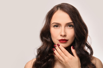 Beautiful young woman with professional manicure on light background