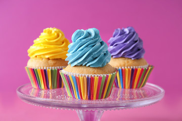 Stand with delicious birthday cupcakes on color background