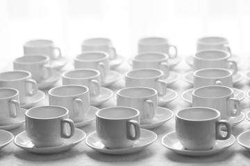 White cups for tea  stacked in line on table with tablecloth for